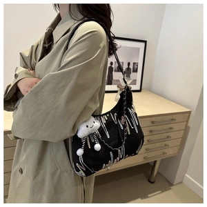 Detail of black canvas tote bag with artistic embroidery and white cloud plush charm