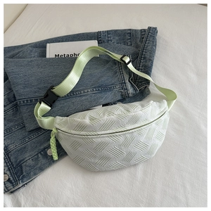 Detail of mint green quilted waist bag with texture on denim jacket background