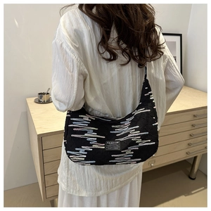 Detail of black underarm bag with wavy textures and Fashion Instinct label on model