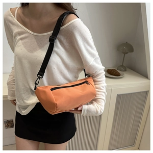 Orange nylon cylinder crossbody bag shown on model for a trendy, casual everyday look