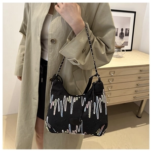 Detail of black canvas crescent bag with colorful wavy embroidery and silver chain strap