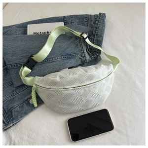Close-up of mint green waist bag with textured fabric, nylon strap and black buckle