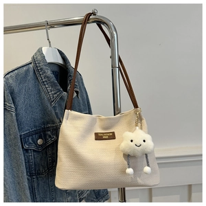 Minimalist beige woven tote bag with brown leather straps and cloud pendant on metal stand