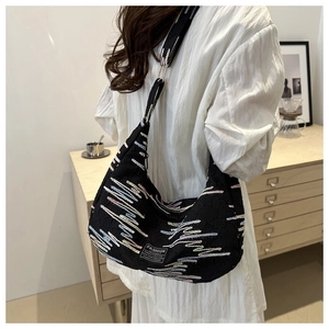 Detail of black nylon crescent bag featuring multi-colored wave embroidery and wide strap