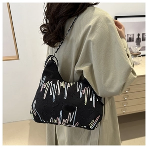 Detail of black shoulder bag with colorful wavy embroidery and silver chain strap
