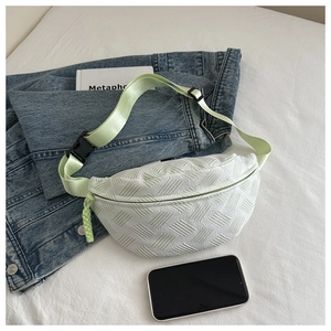 Detail of mint green woven crossbody bag with textured fabric on a lifestyle background