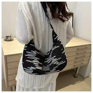 Detailed back view of model wearing black crescent bag with wavy colorful embroidery