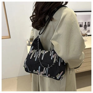 Detail of black tote bag with rainbow wave embroidery and silver chain on model
