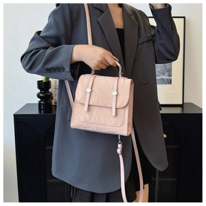 Close-up of light pink pleated leather handbag with silver metallic double buckle straps
