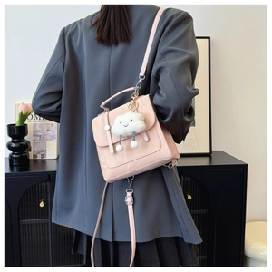 Detail of pink faux leather mini backpack with cute cloud charm worn by a model