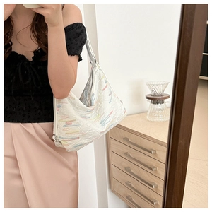 Close-up of white hobo bag with colorful wavy embroidery and embossed texture detail