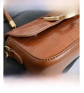 Détail d'un sac sous les bras en cuir marron à motif croco avec boucle dorée