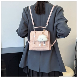 Detail view of pink mini backpack with pleated texture and white cloud plush charm