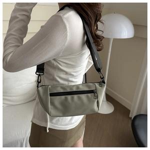 Close-up of light green nylon crossbody bag with black zipper and adjustable strap