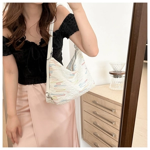 Quilted white shoulder bag with colorful wave embroidery shown on model lifestyle scene