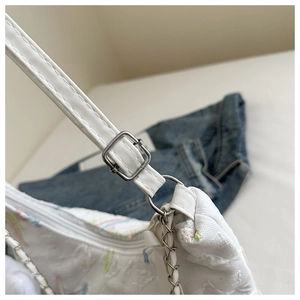 Detail of white bubble texture canvas tote with silver metal buckle and chain strap