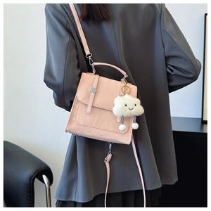 Rear view of a model wearing a pink wrinkled texture backpack with a plush cloud charm