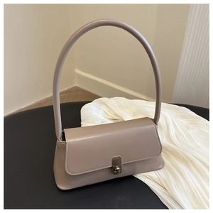 Detail of elegant beige leather handbag featuring a silver twist-lock and rounded handle