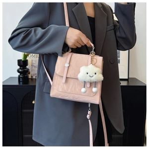 Detail of pink glossy pleated handbag with cute plush cloud charm and silver magnetic buckle