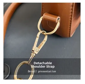 Détail du fermoir mousqueton doré et bandoulière amovible sur sac à main en cuir brun