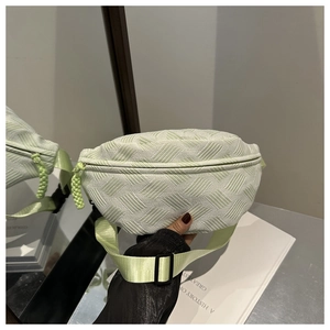 Detail of mint green quilted waist bag showing woven zipper pull and plastic buckle