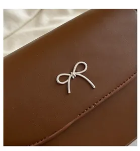 Gros plan d'un sac en cuir marron avec boucle papillon argentée et coutures détaillées