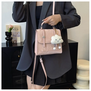 Lichtroze glanzende crossbodytas met wolkjeshanger, getoond op een model in een pak