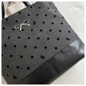 Detail of herringbone pattern fabric tote bag with bow embroidery and metal buckle