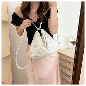 Close-up of white crossbody bag featuring colorful wavy embroidery and slim shoulder straps