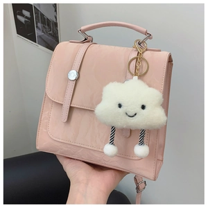 Pink glossy crossbody bag with plush cloud charm and vertical buckle detail
