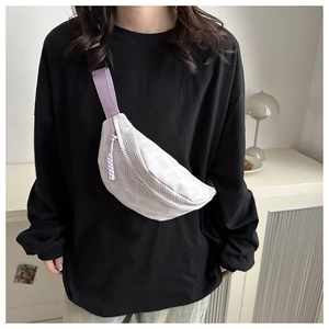 Detalle de bolso bandolera beige texturizado con correa morada usado por una modelo