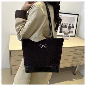 Detailed view of black tote bag with red heart prints and silver bow on model