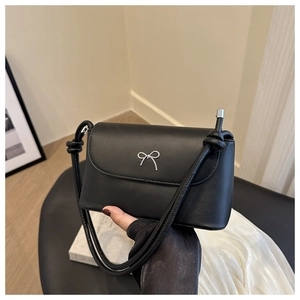 Détail du sac bandoulière noir mat avec boucle papillon argentée et bandoulière nouée