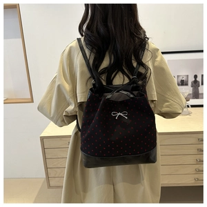 Black canvas bucket backpack with red heart patterns shown on model in trench coat