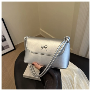 Détail du sac bandoulière argenté en similicuir métallisé avec un nœud décoratif en métal