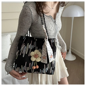 Detail of black canvas tote with colored embroidery, floral charm and printed silk scarf
