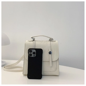 Detailed view of cream leather handbag with silver buckle compared to a smartphone