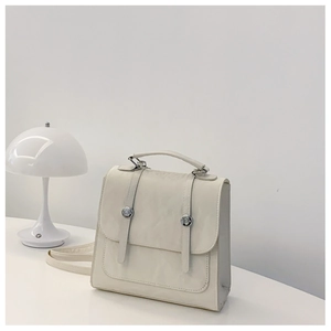 Detail showing white PU leather backpack with silver buckles and vertical decorative straps