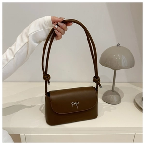 Detail of coffee brown shoulder bag with silver bow accent and slim knotted strap