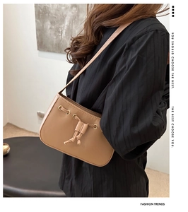 On-model view of a light brown matte leather shoulder bag with decorative drawstring knot