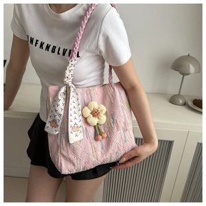 Pink textured tote bag detail with woven handle, floral charm and geometric silk scarf