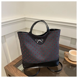 Polished canvas tote bag detail featuring red heart embroidery and silver metal bow