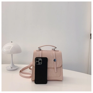 Detail of pink marble textured mini backpack showing size scale next to a smartphone