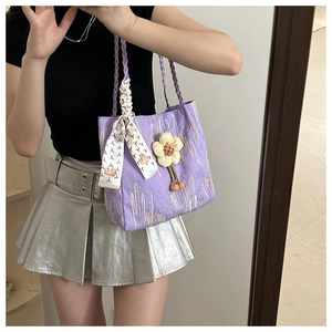 Detailed texture of purple seersucker handbag with floral charm and geometric scarf