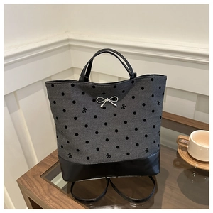 Detail of grey canvas polka dot tote bag with silver metal bow and black leather base