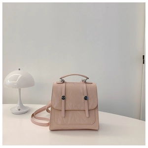 Pale pink glossy leather backpack with silver buckles and decorative vertical straps