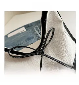 Detail der Fischgräten-Stofftasche mit schwarzem Lederbesatz und dekorativem Knoten