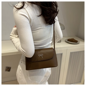 Détail d'un petit sac bandoulière marron avec boucle en métal argenté et nœud élégant