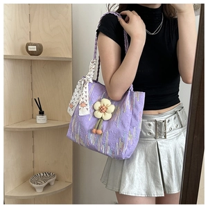 Detail of purple quilted tote bag with wave embroidery and floral silk scarf charm