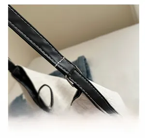 Detail des schwarzen Leder-Schultergurts mit weißen Kontrastnähten an der Tragetasche